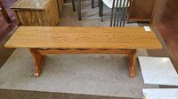 Front view of wooden bench showing flat top surface and supporting legs on carpet