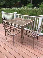 Metal square deck table with visible rust on surface, outdoors on wooden deck.