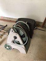 Front angle photo showing two plastic hose reels with attached garden hoses on wheeled carts.