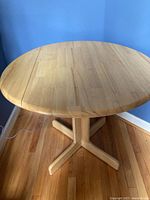 Top-down view of the round wooden table showing dropleaf extended edge and smooth finish.