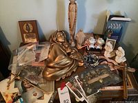 Overview of diverse Catholic religious items on a table including statues, rosaries, prayer cards, books, and crucifixes.