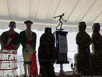 Front view of the first four collectible empty liquor bottles including flamenco dancer, male character, owl, and a soldier figure, with a trophy in between.