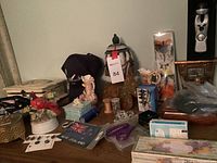 Wide view showing variety of items including jewelry boxes, sewing supplies, decorative figurines, New Zealand patch, and playing cards on a table.