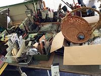 Wide view of the lot showing various tools, drill bits, containers, a wicker basket, and some lighting fixtures on a table near a window.