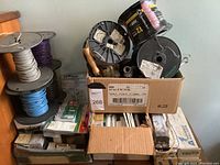 Overall view of multiple spools of insulated copper wire and cardboard box of components