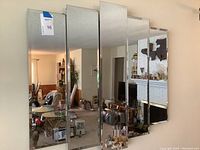 Front view of six-panel wall-mounted mirror reflecting living room and adjacent spaces
