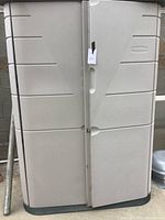 Front view of closed beige Rubbermaid storage cabinet with double doors and molded panel design