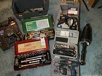 Photo showing multiple socket wrench sets, cordless drill, Dremel rotary tool, 6 inch buffer, plunger tool, and the large empty plastic toolbox