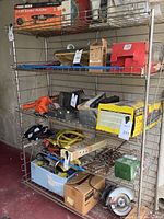 Full view of the metal wire utility shelf filled with boxes and tools. Photo taken to show the shelf which is the lot item. Contents are excluded from sale per seller.