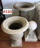 Two urn-shaped composite jardineres and one spherical patio decoration on square base placed together for scale and condition view.