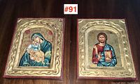 Front view of two religious icons showing Virgin Mary with baby Jesus and Jesus Christ, mounted on wood with gold textured borders.