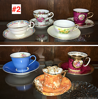 Full view of several porcelain tea cups and matching saucers arranged on a shelf with a reflective surface and wood background