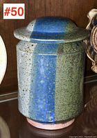 Front and side view of pottery canister showing vertical blue and green speckled glaze with lid on.