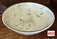 Top-down view showing inside and shape of speckled glazed pottery bowl.