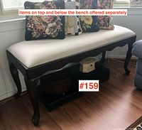 Bench with beige upholstered seat and mahogany finish on frame showing curved legs with claw feet