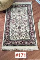 Full view of small rectangular carpet featuring floral pattern and fringed ends.