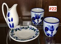 Set showing white stoneware pitcher with cobalt blue leaves, two matching cups with blue floral decoration, and a leafy décor plate