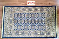 Top-down view of rectangular carpet showing overall design and color pattern against a wooden floor.