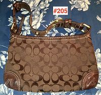 Photo of Coach handbag front showing signature 'C' pattern and leather corner trim on blue floral background.