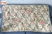 Full view of hooked needlework wall hanging showing overall floral lattice pattern and border.