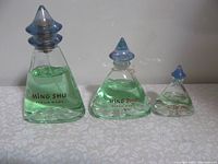 Three Ming Shu Fleur Rare perfume bottles in different sizes standing side by side showing the overall design and liquid inside.