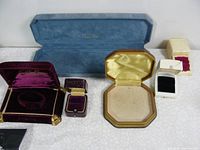 Six vintage jewelry boxes arranged on a patterned surface, showing different colors and sizes.