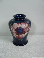 Front view of the vase showing large pink flower on dark blue background.