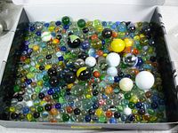 Box containing a large assortment of vintage glass marbles in various colors and sizes, displayed from above.