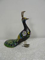 Side view of the cloisonné pheasant figurine showing colorful enamel floral and feather patterns and brass crest.