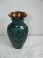 Full view of a large hand hammered copper vase showing the interior copper finish and exterior green patina.