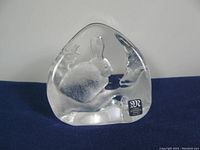 Angled view of the clear lead glass paperweight showing the detailed etched hare and moon inside the glass with the Mats Jonasson label.