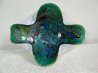Top angled view showing the colorful, motifs in multiple hues within the organic-shaped glass dish interior.