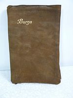 Photo of the front suede cover with gold text 'Burgs',' showing material texture and wear.