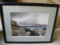 Framed landscape print showing rocky shoreline and water with cloudy sky