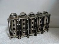 Front view of vintage metal coin holder with five compartments and coin slots on top.