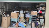 Wide shot of storage unit interior showing boxes, shelving, lamps, pillows, art and furniture