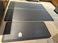Three black rubber mats arranged on floor, two larger mats (61" x 24") and one smaller mat (42" x 20") showing overall lot contents and size comparison.