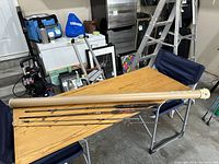 Photo showing four fishing rods of different styles and lengths laid out on a table with protective beige tube beside them