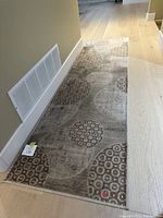 Hallway carpet runner laid out on a wooden floor showing the full length with circular pattern design.
