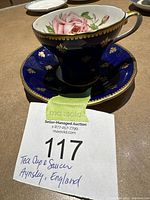 Photo of vintage Aynsley bone china tea cup and saucer set, with cobalt blue, gold fleur-de-lis pattern and pink rose interior design.
