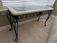 Side angle showing the wrought iron curved legs and arch detail along the sides of the sofa table.