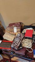 Overview of assorted vintage clutches and handbags arranged on a table, highlighting textures and colors such as burgundy, gold, beige, black, and snakeskin