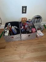 Two fabric storage bins containing assorted soaps, lotions, fragrances and a silver brush case