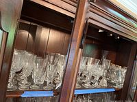 Shelf display of assorted crystal stemware including wine glasses and smaller glasses.