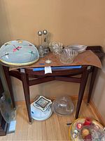 Demilune wooden table from front angle with decorative items on top and below (items not included).