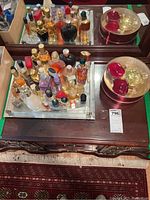 Overview of assorted perfume bottles on mirrored tray with vanity mirror in background