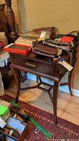 Wood nightstand with drawer and curved legs holding various bags and items, showing top and front drawer.