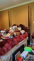 Oblique view of queen bed showing red linens, mattress frame, and assorted items on the bed surface.
