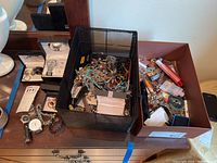 Overview of dresser top showing black box with mixed loose jewelry, brown box, loose watches and bracelets