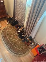 Wide view of various women’s shoes arranged on floor carpet near a window with boxes.
